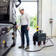 Technician in a hard hat DC fast charging an electric truck in a workshop