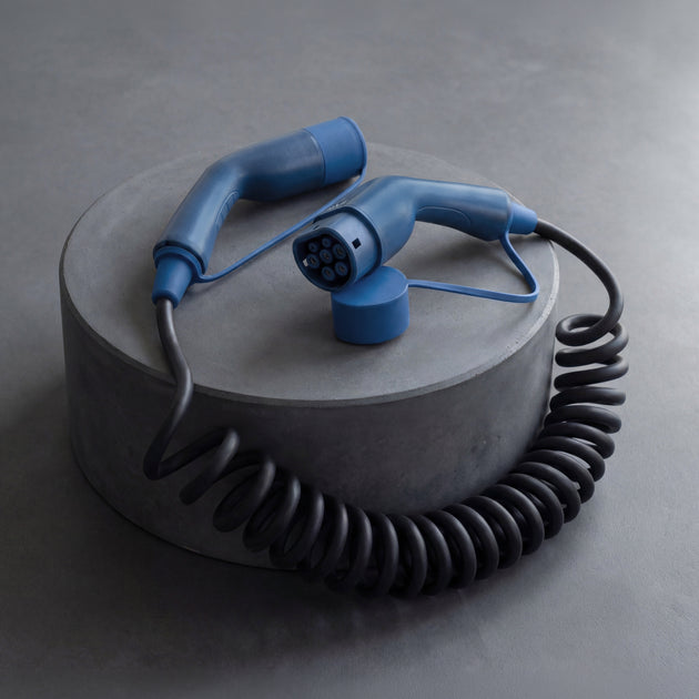 Spiral Type 2 charging cable with blue connectors on a concrete studio pedestal